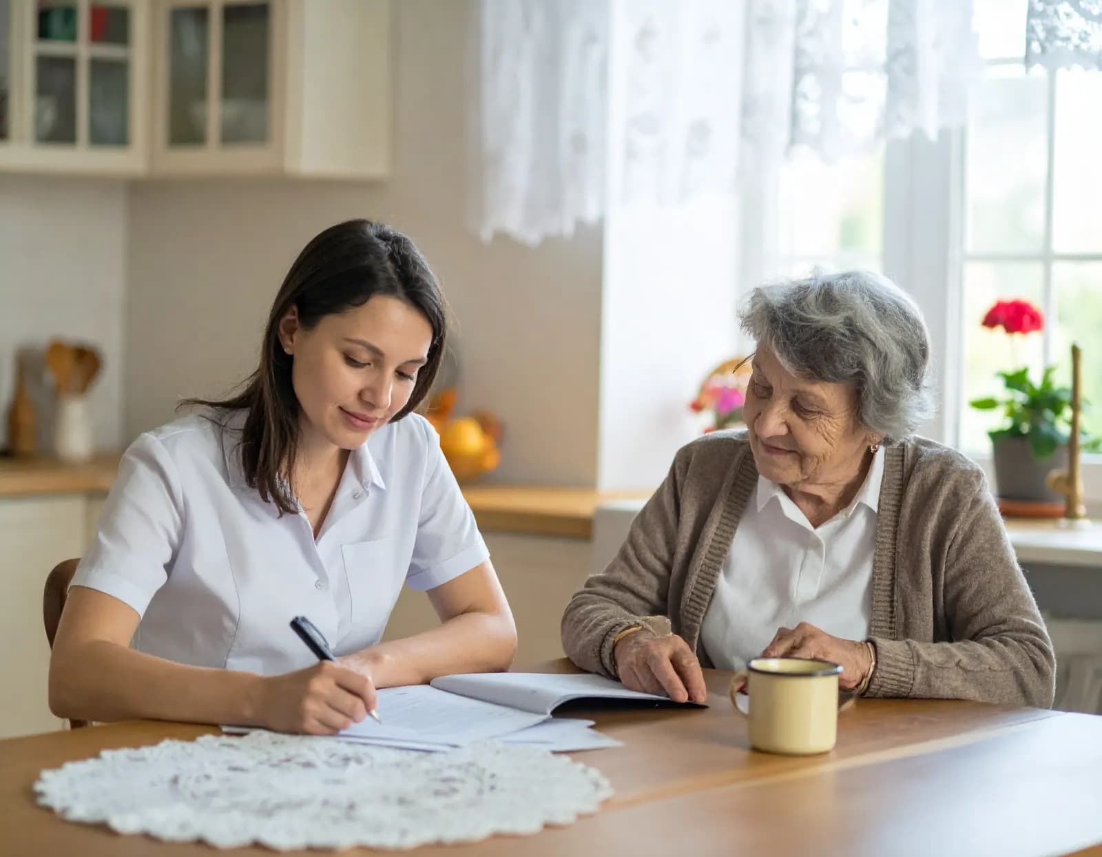 Îngrijitoare care completează acte la masă alături de o femeie vârstnică
