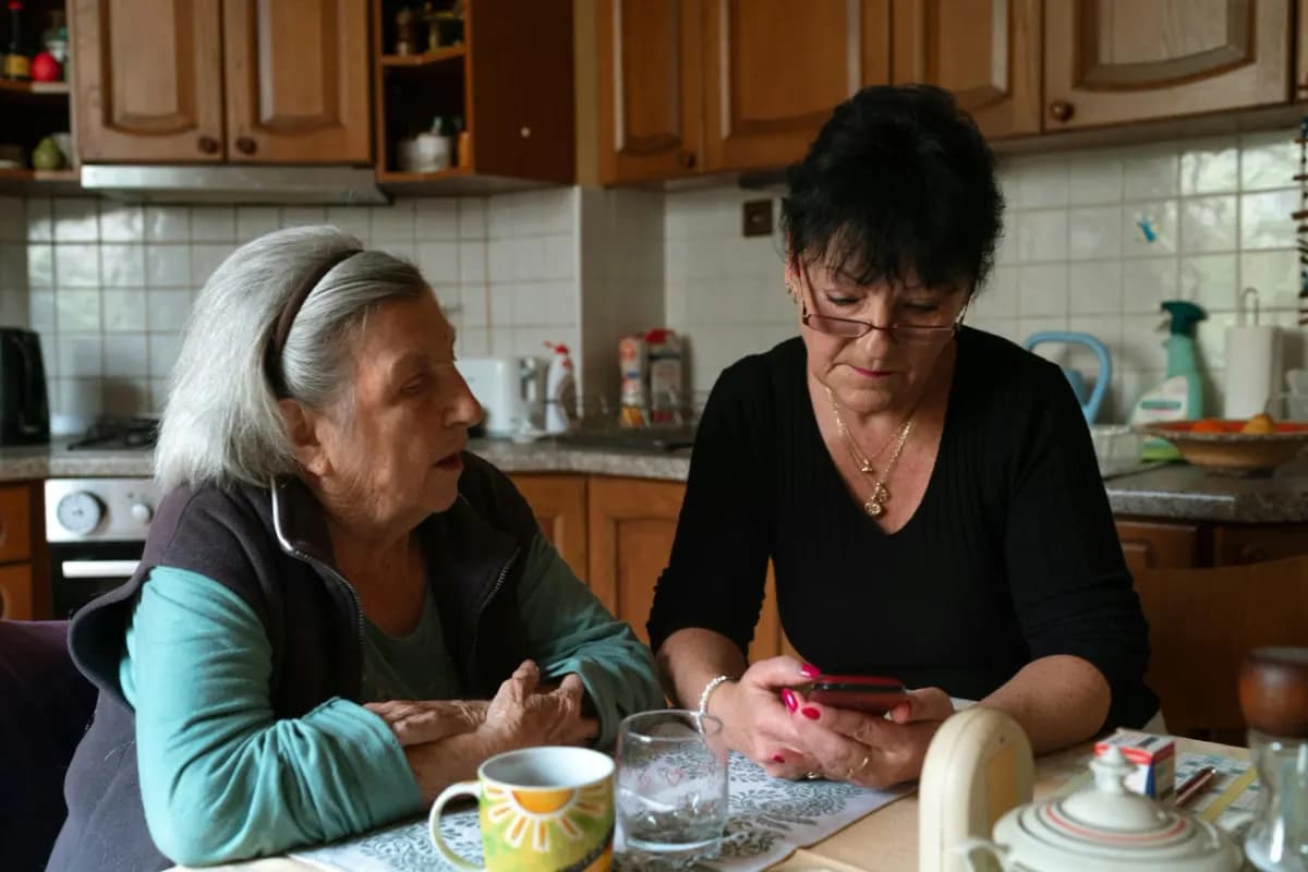 O îngrijitoare și o doamnă în vârstă, la masa din bucătărie