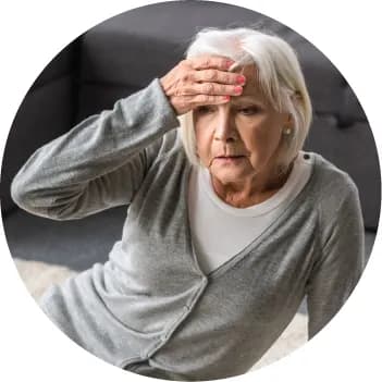 O doamnă în vârstă, cu mâna la frunte, acasă